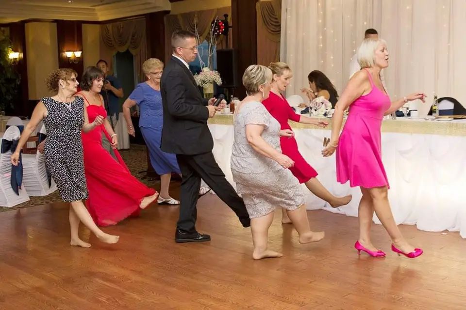 Wedding guests dancing in a line across a packed reception dance floor
